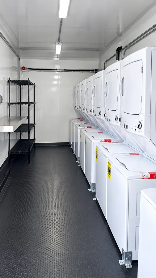 Rows of stacked washers and dryers inside a laundry trailer